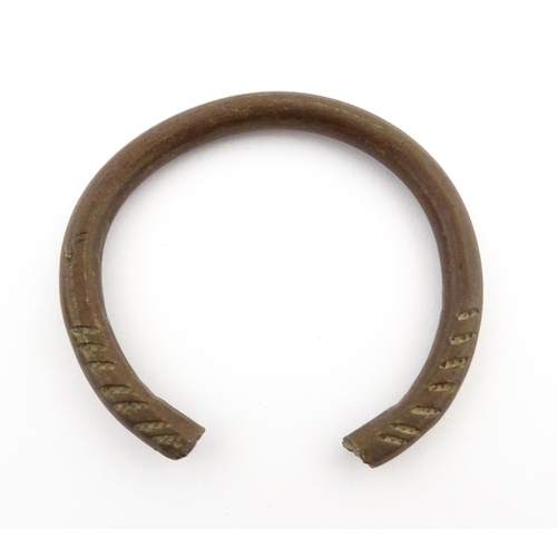 1123 - A manilla currency bracelet / bangle with incised detail. Approx. 2 1/2