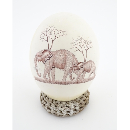 1143 - An ostrich egg with engraved decoration depicting an African elephant and calf. Signed Rodger Ndlovu... 