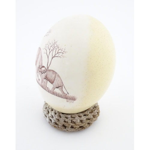 1143 - An ostrich egg with engraved decoration depicting an African elephant and calf. Signed Rodger Ndlovu... 