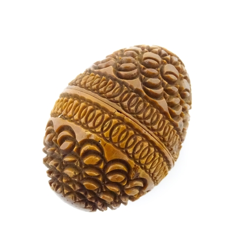 1153 - A 19thC carved coquilla nut of egg form with silver sewing thimble within, hallmarked Chester 1900, ... 