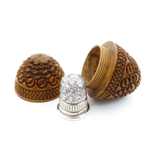 1153 - A 19thC carved coquilla nut of egg form with silver sewing thimble within, hallmarked Chester 1900, ... 