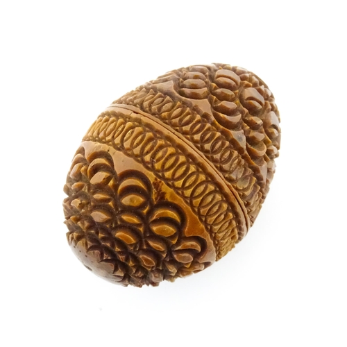 1153 - A 19thC carved coquilla nut of egg form with silver sewing thimble within, hallmarked Chester 1900, ... 