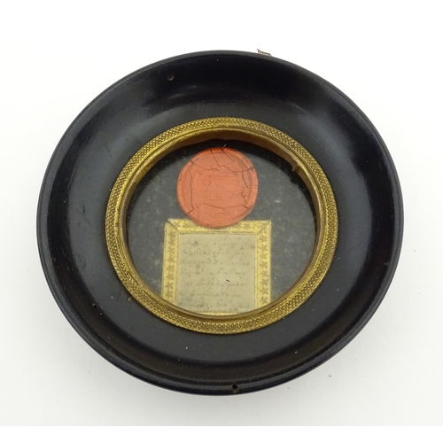 1195 - A 19thC wax seal depicting a heraldic shield, with handwritten note under. Within an ebonised circul... 