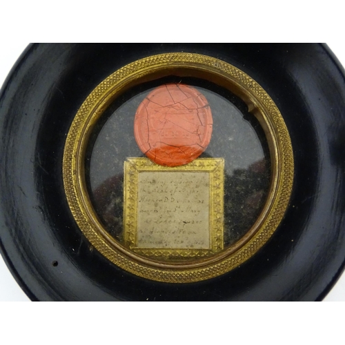 1195 - A 19thC wax seal depicting a heraldic shield, with handwritten note under. Within an ebonised circul... 