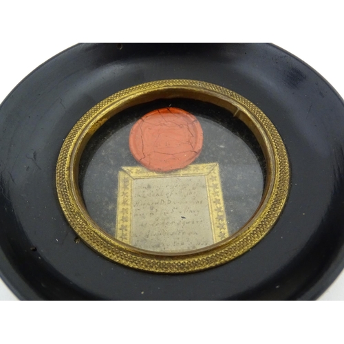 1195 - A 19thC wax seal depicting a heraldic shield, with handwritten note under. Within an ebonised circul... 