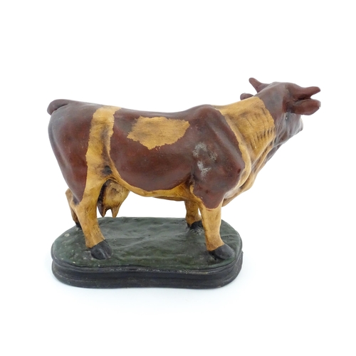 1264 - A 20thC fibreglass model of a cow with painted decoration. Approx. 13 1/4