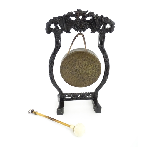 1274 - A 20thC Chinese gong and beater, the carved hardwood stand with central mask detail and scrolling st... 