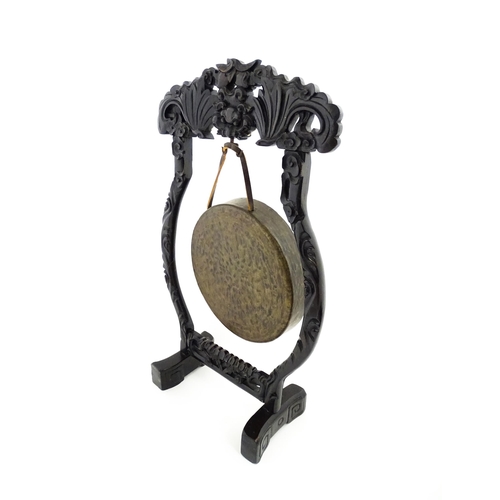 1274 - A 20thC Chinese gong and beater, the carved hardwood stand with central mask detail and scrolling st... 