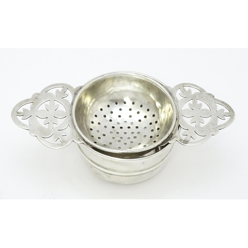 533 - A silver twin handled tea strainer and stand, hallmarked Sheffield 1958, maker Viner's Ltd. Approx. ... 