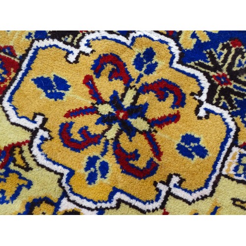 1503 - Carpet / Rug : A yellow and ochre ground rug with blue, red and white floral and foliate decoration,... 