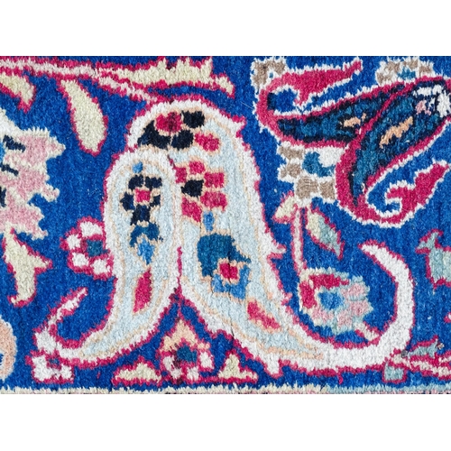 1507 - Carpet / Rug: A blue ground carpet with central cream and red floral motif bordered by scrolling fol... 