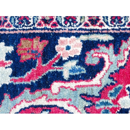 1507 - Carpet / Rug: A blue ground carpet with central cream and red floral motif bordered by scrolling fol... 