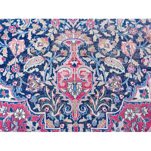 1507 - Carpet / Rug: A blue ground carpet with central cream and red floral motif bordered by scrolling fol... 