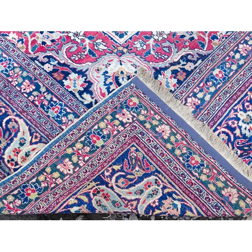 1507 - Carpet / Rug: A blue ground carpet with central cream and red floral motif bordered by scrolling fol... 