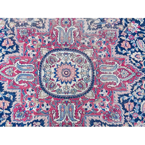 1507 - Carpet / Rug: A blue ground carpet with central cream and red floral motif bordered by scrolling fol... 