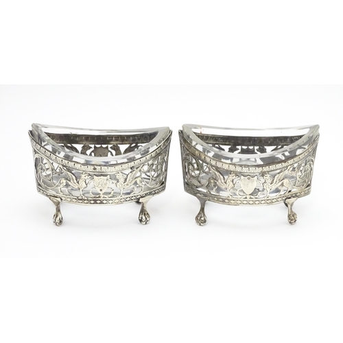 456 - A pair of white metal salts with griffin detail and clear glass liners. Together with a silver peppe... 