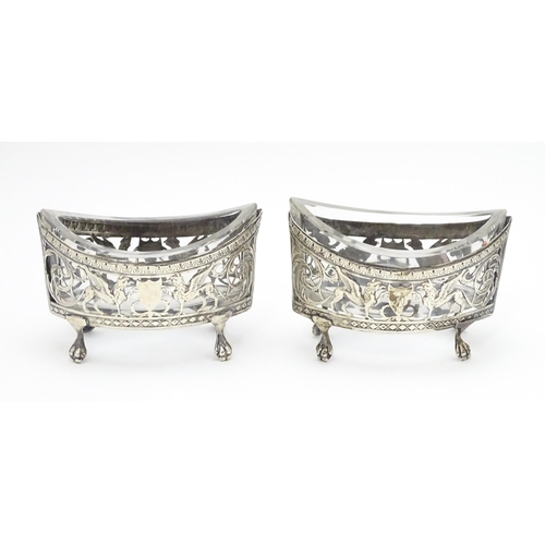 456 - A pair of white metal salts with griffin detail and clear glass liners. Together with a silver peppe... 