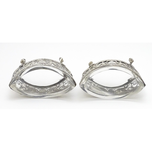 456 - A pair of white metal salts with griffin detail and clear glass liners. Together with a silver peppe... 