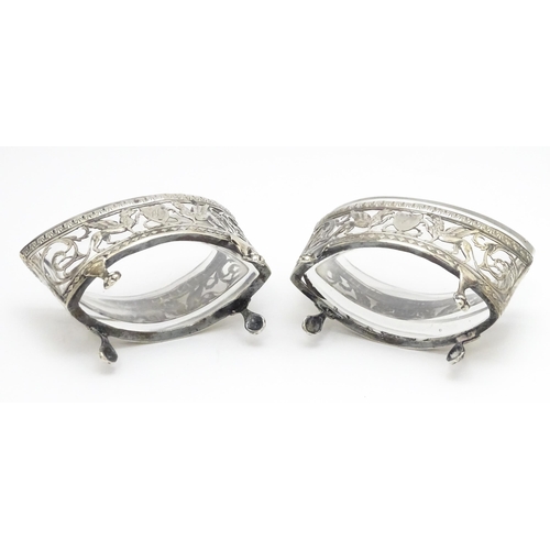 456 - A pair of white metal salts with griffin detail and clear glass liners. Together with a silver peppe... 