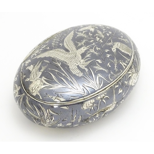 467 - A Continental white metal snuff box of oval form with niello decoration depicting birds, nests, inse... 