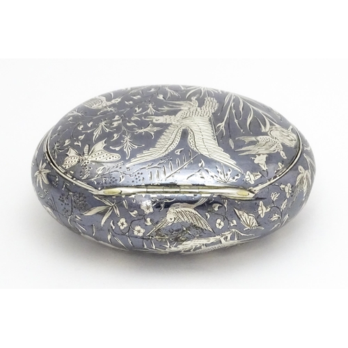 467 - A Continental white metal snuff box of oval form with niello decoration depicting birds, nests, inse... 