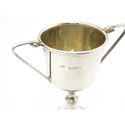 516 - A miniature silver twin handled trophy cup hallmarked Birmingham 1934, maker William Adams Ltd. Toge... 