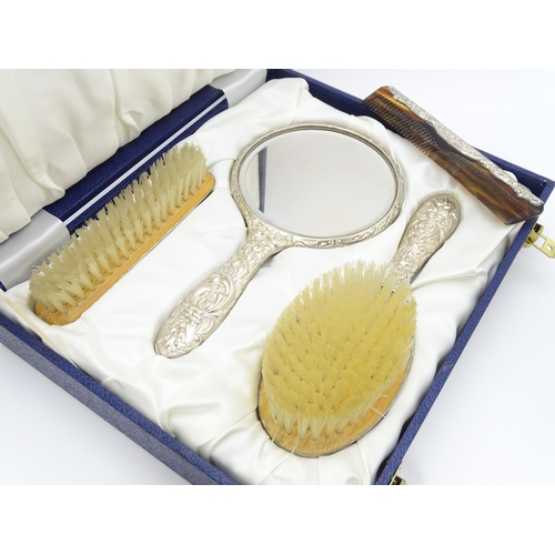 618 - A cased four piece dressing table set comprising silver hand mirror, brushes and comb. Hallmarked Bi... 