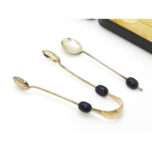 643 - A cased set of six silver coffee bean spoons with sugar tongs en suite, each with coffee bean finial... 