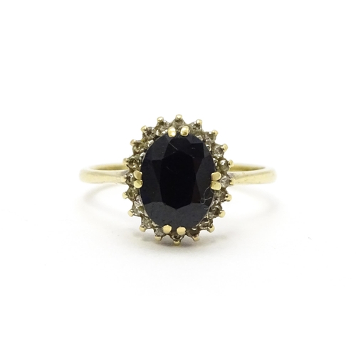 701 - A 9ct gold ring set with central sapphire bordered by diamonds. Ring size approx. P