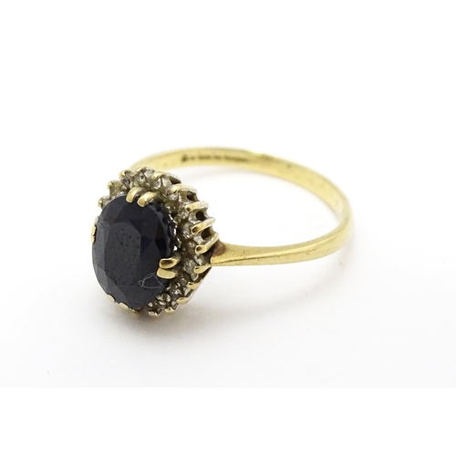 701 - A 9ct gold ring set with central sapphire bordered by diamonds. Ring size approx. P