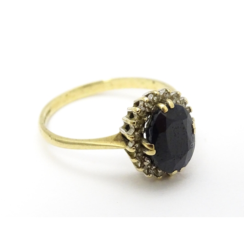 701 - A 9ct gold ring set with central sapphire bordered by diamonds. Ring size approx. P