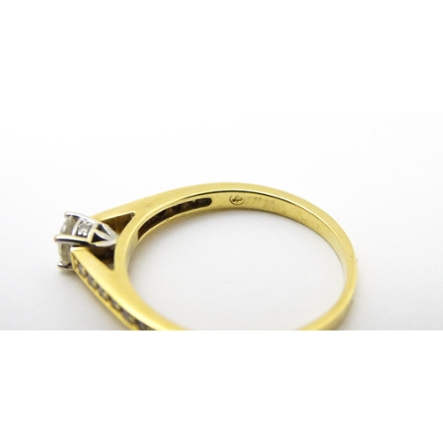 705 - An 18ct gold ring set with a central diamond flanked by further diamonds to shoulders. Ring size app... 