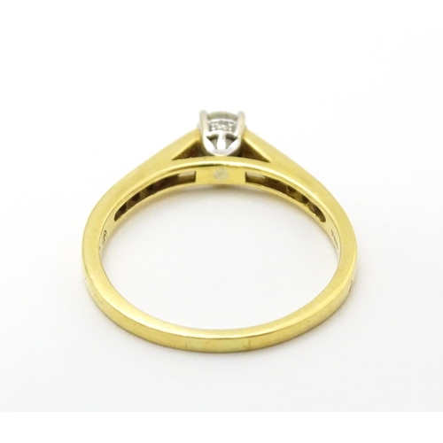 705 - An 18ct gold ring set with a central diamond flanked by further diamonds to shoulders. Ring size app... 