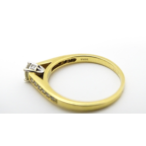 705 - An 18ct gold ring set with a central diamond flanked by further diamonds to shoulders. Ring size app... 