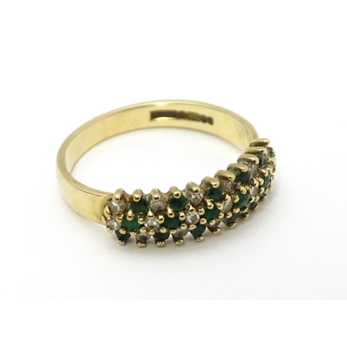 709 - A 9ct gold ring set with emeralds and diamonds. Ring size approx. K