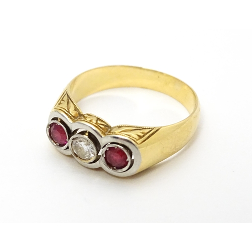 711 - A yellow gold ring set with central diamond  flanked by rubies. Ring size approx. P