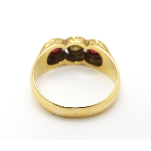 711 - A yellow gold ring set with central diamond  flanked by rubies. Ring size approx. P