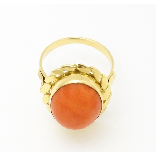 714 - A yellow metal ring set with coral cabochon. Ring size approx. K