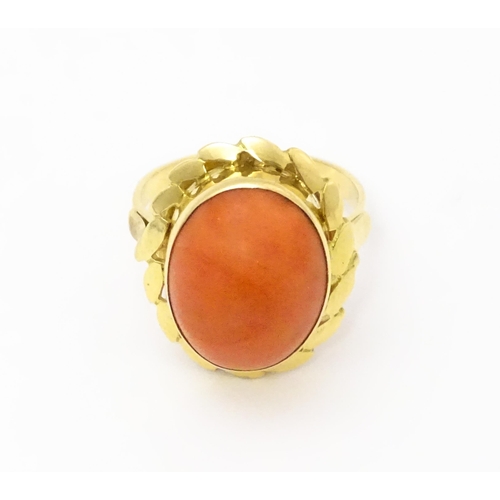 714 - A yellow metal ring set with coral cabochon. Ring size approx. K