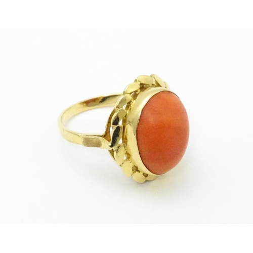 714 - A yellow metal ring set with coral cabochon. Ring size approx. K