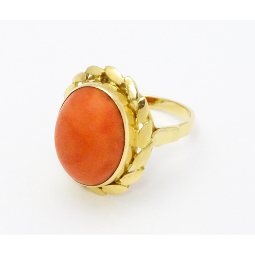 714 - A yellow metal ring set with coral cabochon. Ring size approx. K