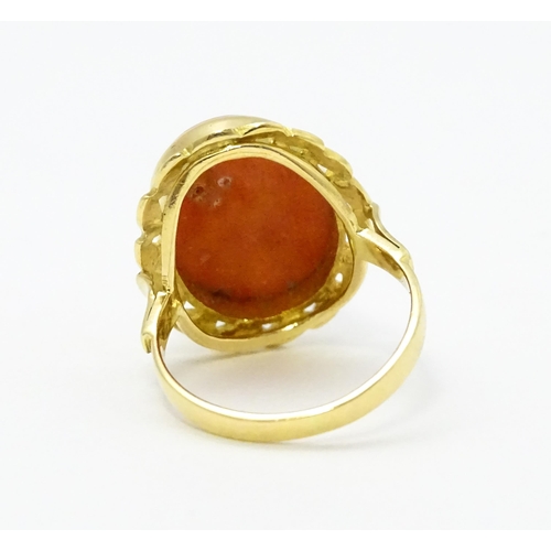 714 - A yellow metal ring set with coral cabochon. Ring size approx. K