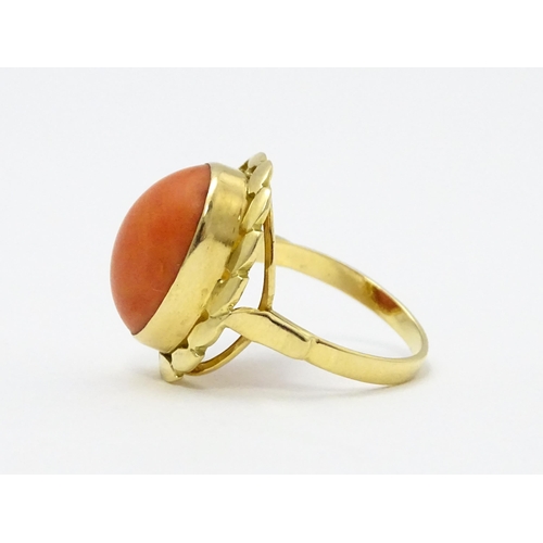 714 - A yellow metal ring set with coral cabochon. Ring size approx. K