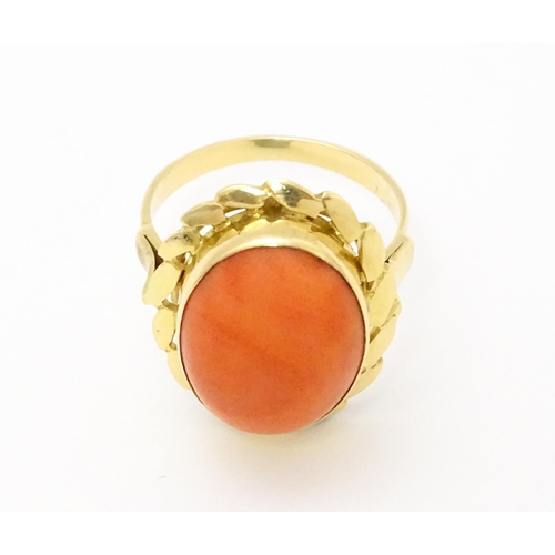 714 - A yellow metal ring set with coral cabochon. Ring size approx. K