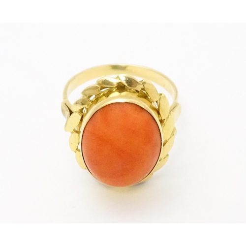 714 - A yellow metal ring set with coral cabochon. Ring size approx. K