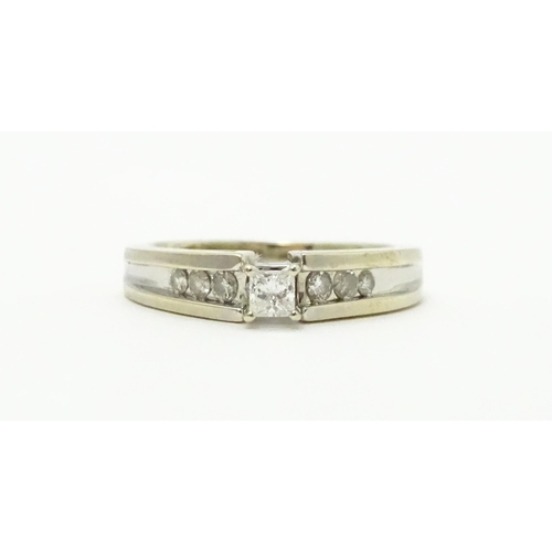 717 - A 14ct white gold ring set with central diamond flanked by further diamonds to shoulders. Ring size ... 