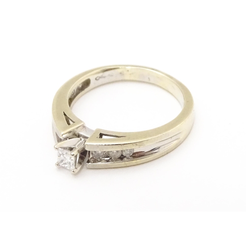 717 - A 14ct white gold ring set with central diamond flanked by further diamonds to shoulders. Ring size ... 