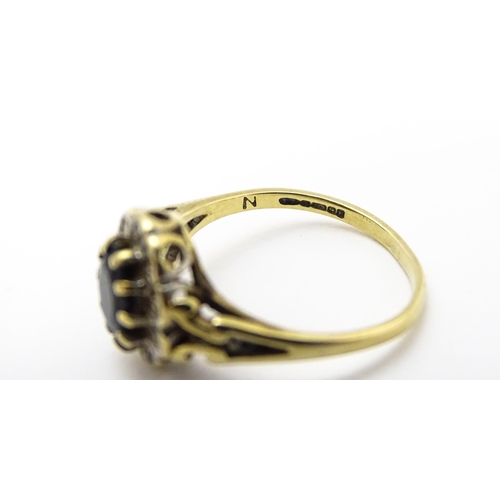 723 - A 9ct gold ring set with central sapphire bordered by diamonds. Ring size approx.  L 1/2