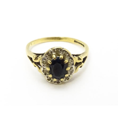 723 - A 9ct gold ring set with central sapphire bordered by diamonds. Ring size approx.  L 1/2