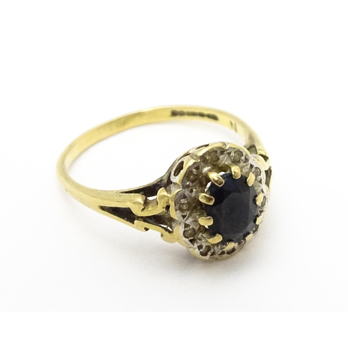 723 - A 9ct gold ring set with central sapphire bordered by diamonds. Ring size approx.  L 1/2